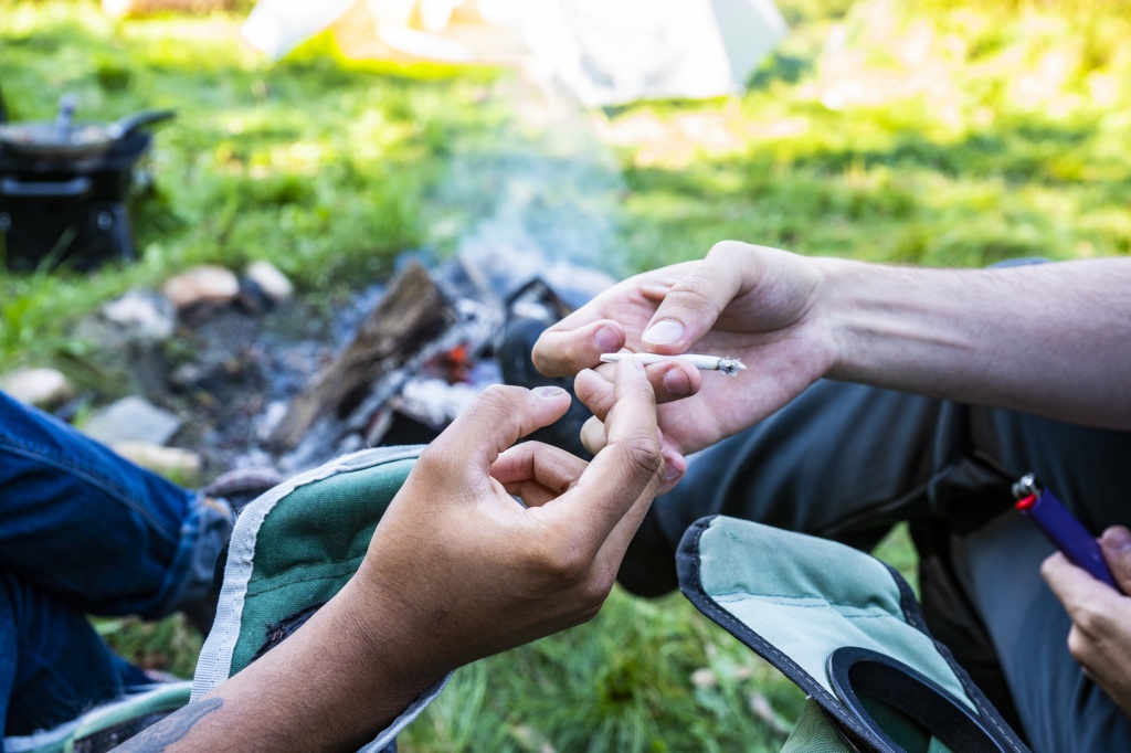Two people sharing a joint beside a campfire