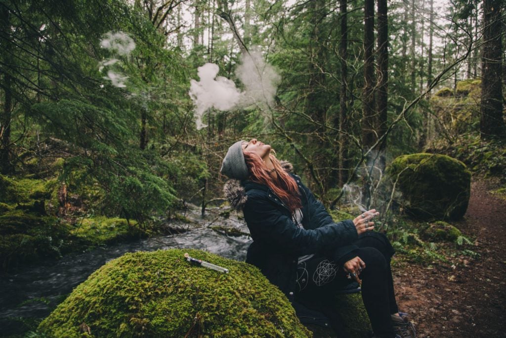Woman exhaling vapor in the woods