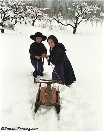 Amish children pulling a sled through fresh snow